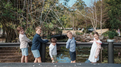 Large extended family group portrait at Gold Coast Regional Botanic Gardens featuring coordinated colorful outfits and a lush green backdrop.