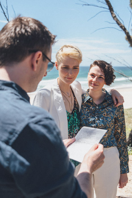 Midday elopement at Kingscliff Beach with two brides sharing candid, emotional moments by the shore.