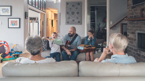 A contact sheet of candid indoor family photography. The images capture a mother, father, and two young children engaging in everyday activities