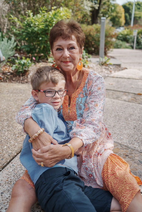Large extended family group portrait at Gold Coast Regional Botanic Gardens featuring coordinated colorful outfits and a lush green backdrop.