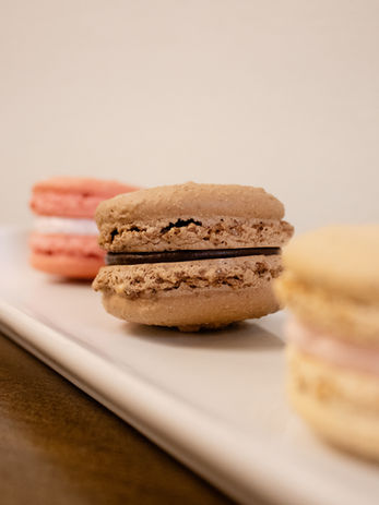 Three macarons with a chocolate macaron in focus.