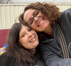 Two women check to cheek sharing their smiles
