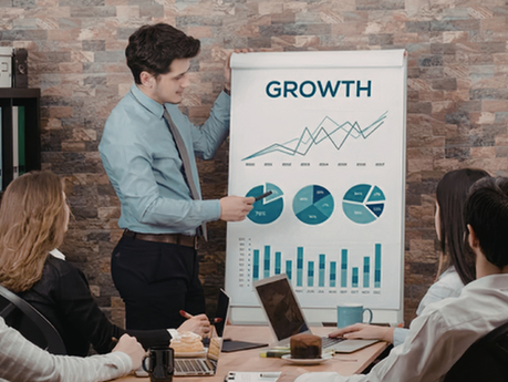 Man presenting a growth chart to coworkers in a conference room.