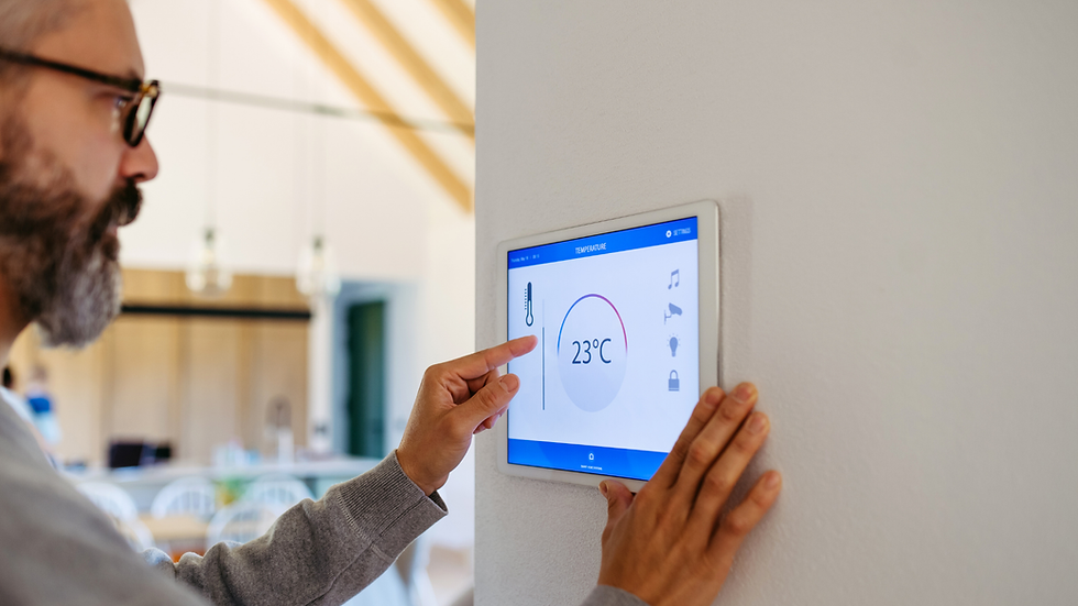 A person adjusts a wall-mounted digital thermostat showing 23°C. The background features a modern interior with warm lighting.
