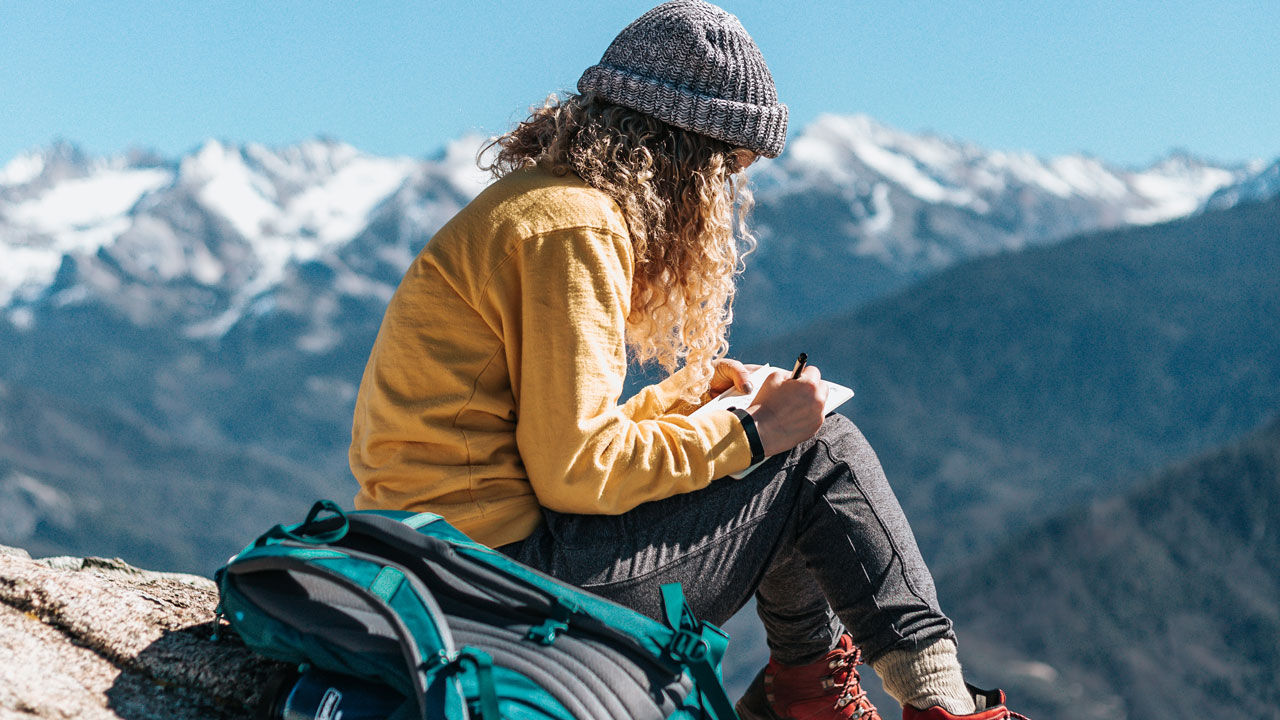 women sitting on mountain writing about dreams and money
