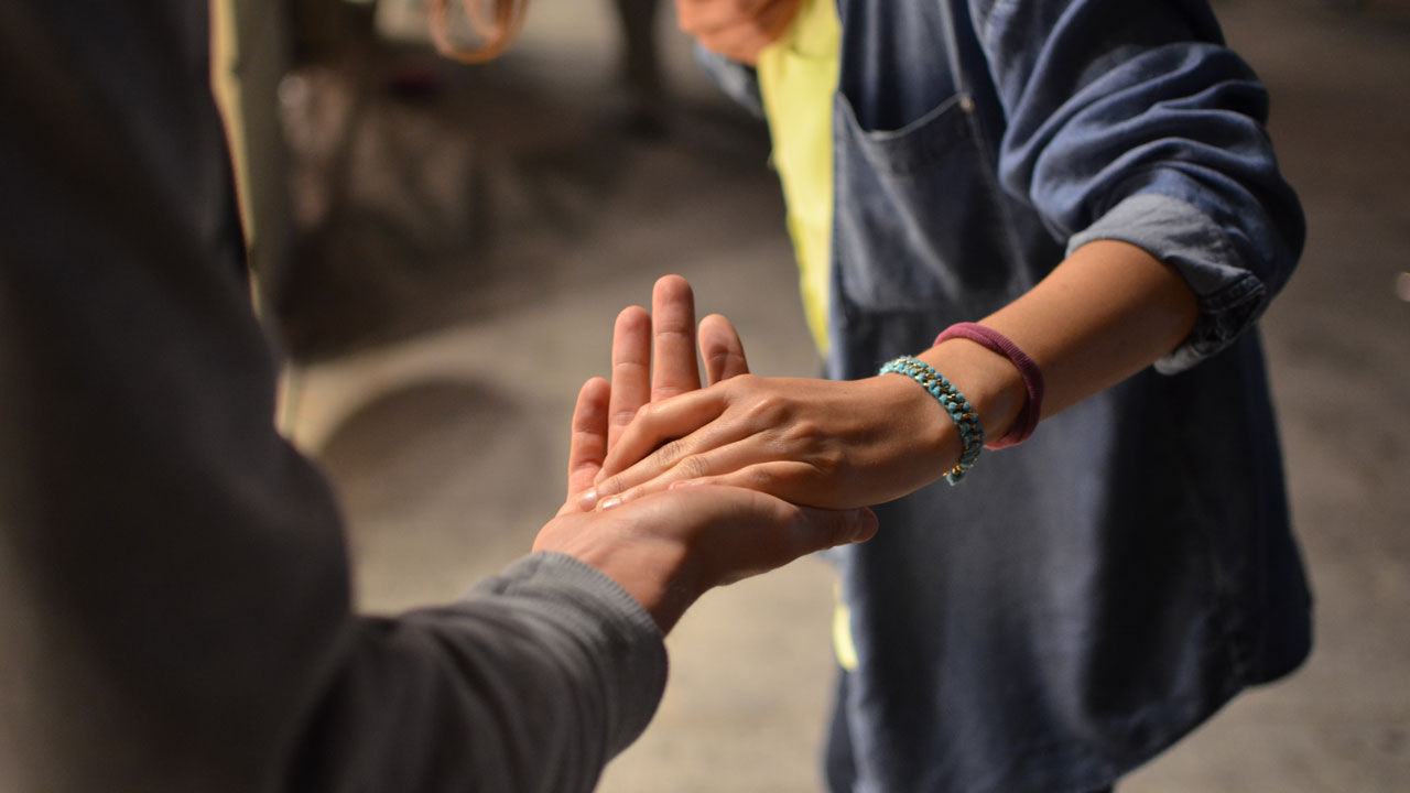 Two persons holding hands on the street.