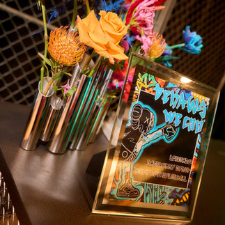 Close-up of colorful floral arrangements displayed beside a custom mocktail menu, styled for a graffiti-inspired bar mitzvah celebration.