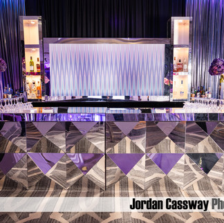 Luxury mirrored Bat Mitzvah bar with geometric mirrored panels, purple floral arrangements, and illuminated back bar at Green Valley Country Club.