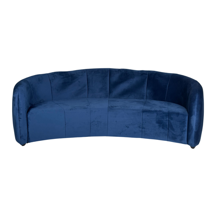 Indigo blue velvet curved sofa with a rounded back, channel-stitched detailing, and a contemporary silhouette.