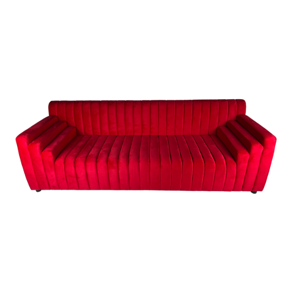 Ruby red velvet sofa with vertical channel tufting, wide arms, and a low-profile modern design.