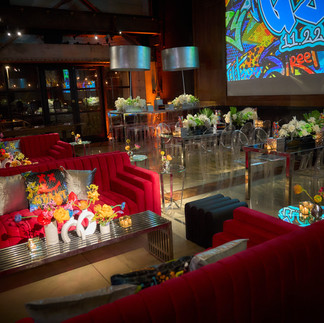 Graffiti-inspired event space featuring modern lounge pods, clear dining tables, and bold graphic accents styled for a bar mitzvah celebration.