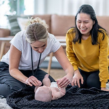 Two happy women knealing on the floor playing with a baby