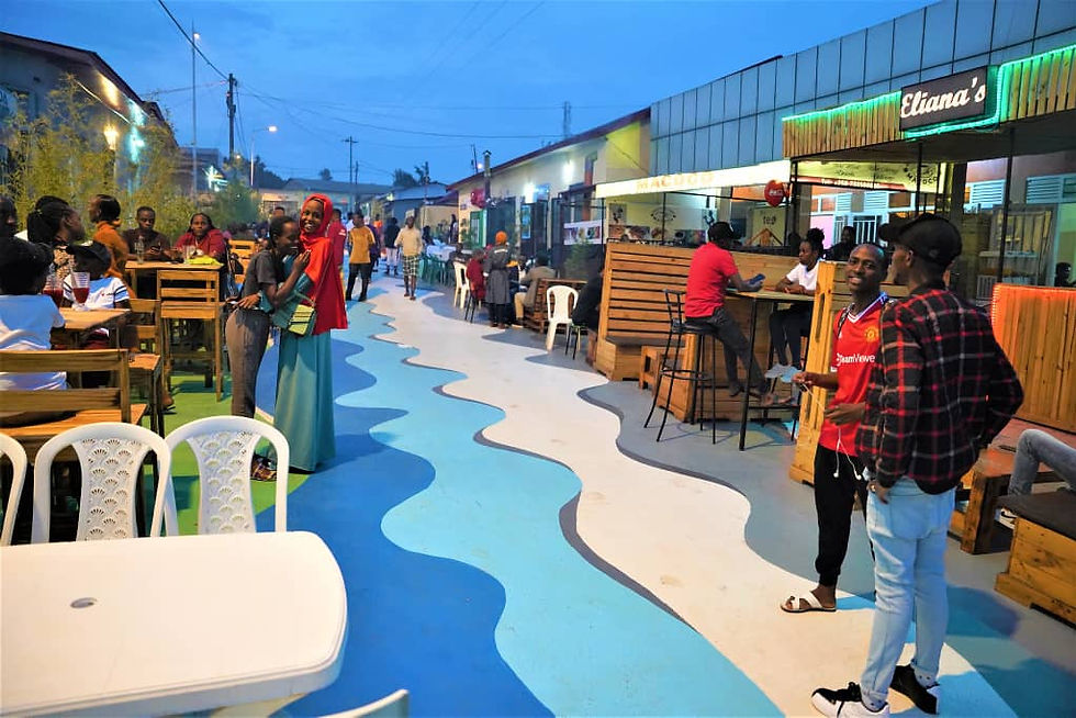 Locals and tourists sharing laughter and enjoying Rwandan street food at Nyamirambo Car-Free Zone in Kigali