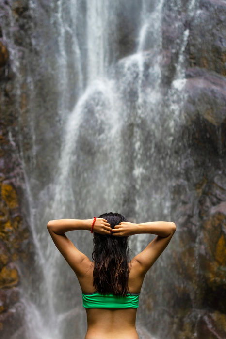 A woman sitting near a waterfall during the Journey to Reconnect and Rise women-only retreat in Rwanda