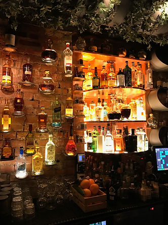 Backlit shelves of liquor bottles inside a cozy Copenhagen bar with exposed brick walls