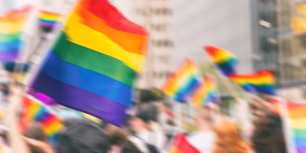 Foto von einer Pride Parade mit vielen unscharfen Flaggen der LGBTQIA+ Community