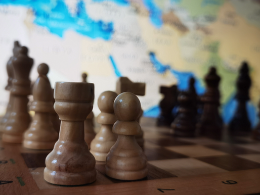 A stylized globe designed as a chessboard, with chess pieces marked 'EU' and 'Mercosur' aligned on one side, facing opposing pieces labeled 'China' and 'USA' on the other. The board rests on a turbulent sea, symbolizing global instability, while a faint light breaks through storm clouds above — representing strategic alliances amid geopolitical tension.