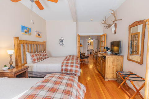 A hotel room with antlers mounted on the wall and two beds with plaid sheets and wooden headboards