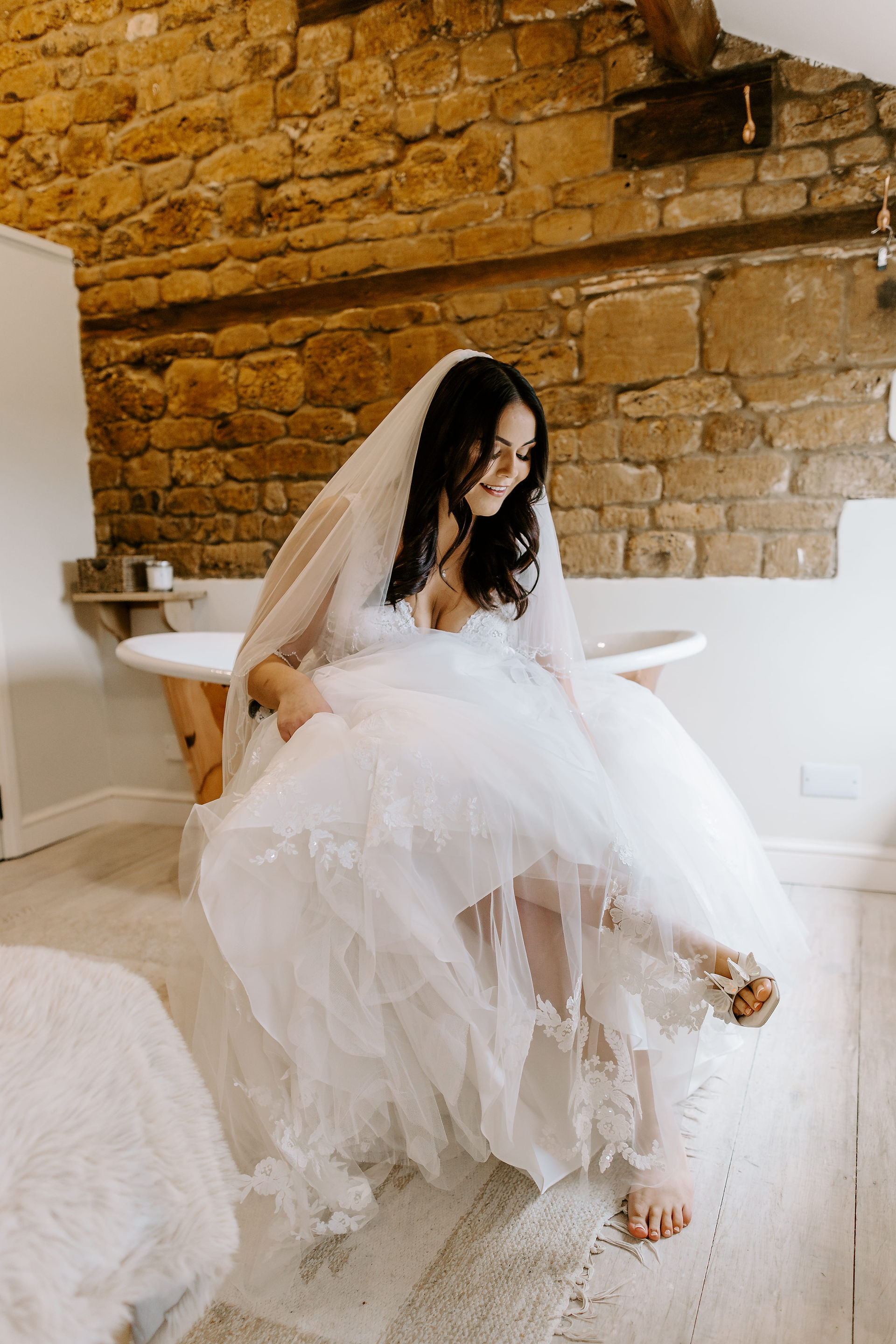 Portrait of the bride standing by the window, light falling across her face and dress.
