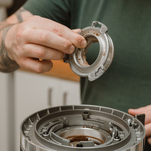 Barista tar ut den øverste kniven fra kverna