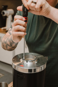 Barista skrur ut skruene på malingsgrad skiven.