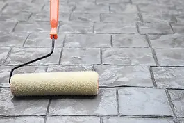 Applying a clear sealer to a concrete surface with a roller to protect against moisture and wear during concrete sealing by Level Best Northwest