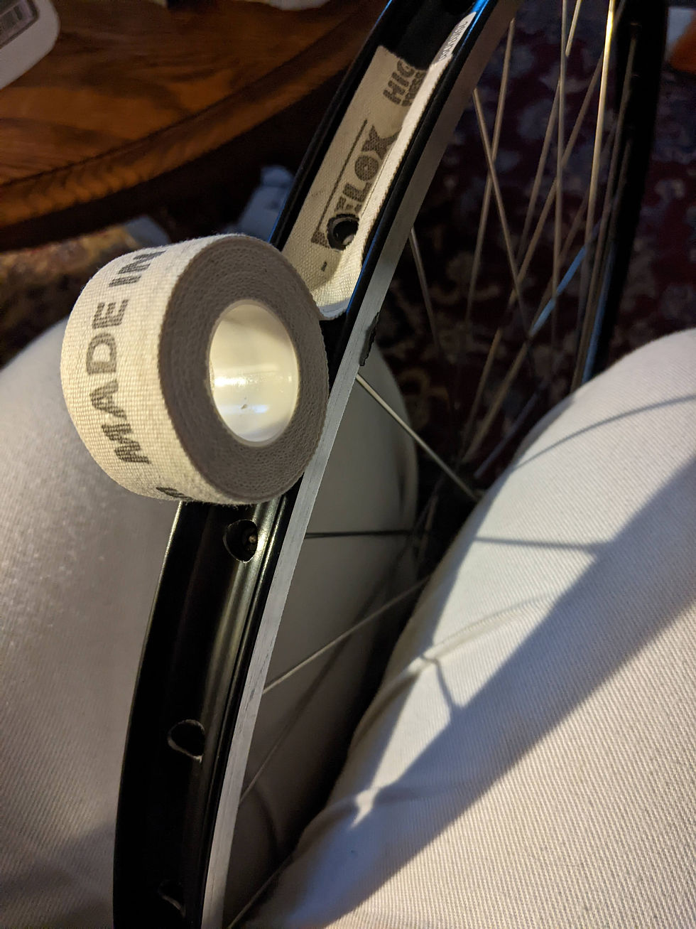 Cream-colored rim tape getting rolled onto the inside of the rim.