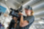 A student operates a professional camera at a live sporting event.