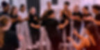 Teen girls clap and smile around a dancer in a studio, cheering during a lively dance class.