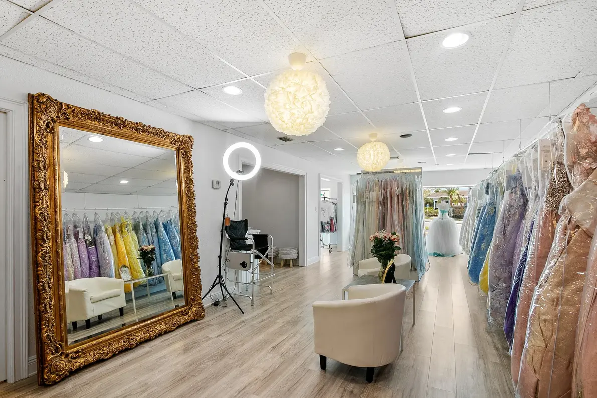 Boutique interior with gown racks, glam lighting, and large decorative mirror