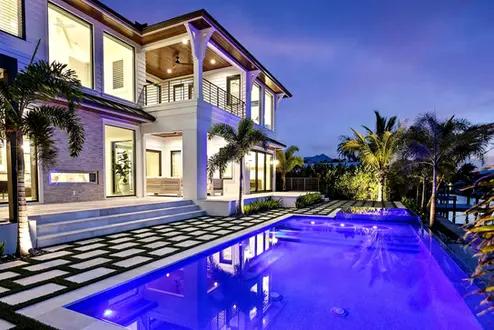 High-end property exterior with pool and garden lighting at dusk