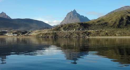 Paisaje del mar en las costas de Ushuaia donde el pico de una montaña se espeja en el agua serena y simboliza la idea de "responder como acto de presencia".
