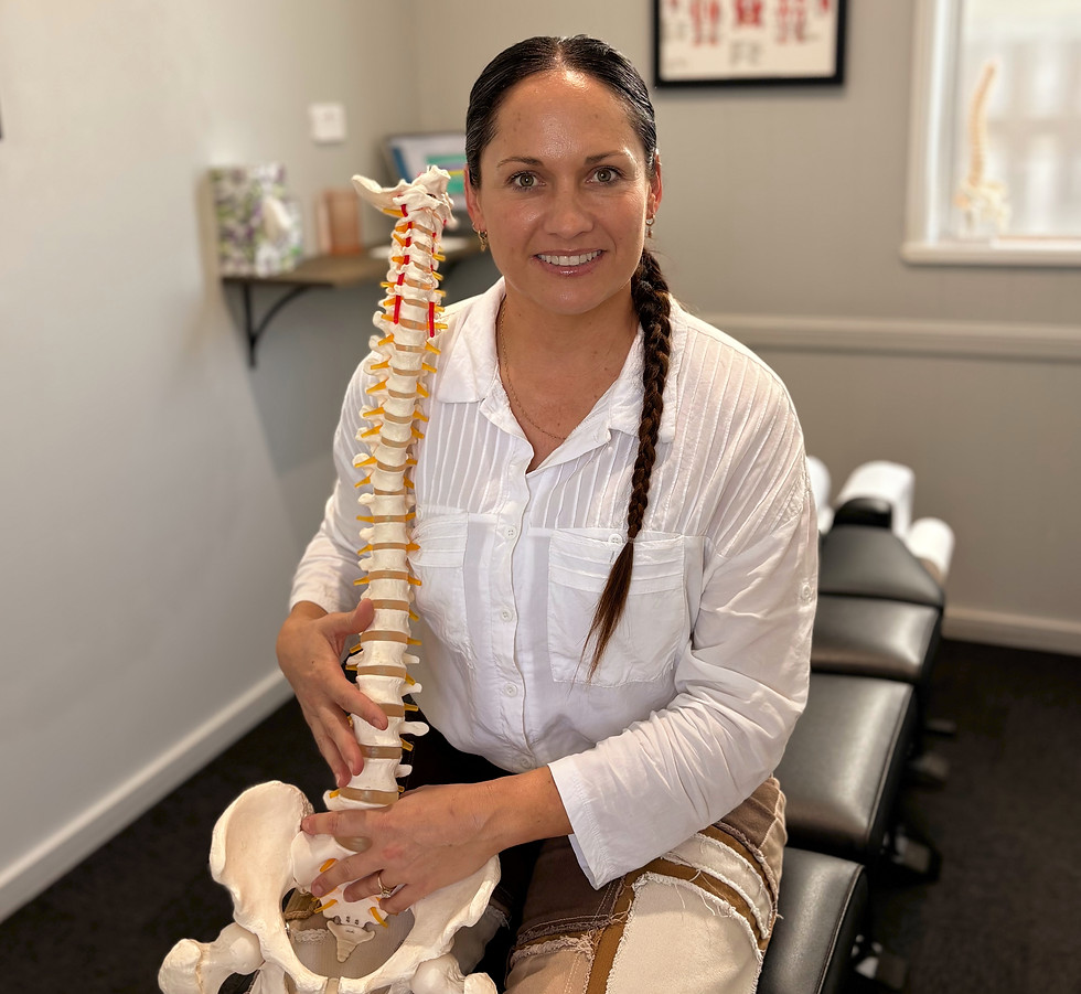Sarina chiropractor smiling with a human spine model.