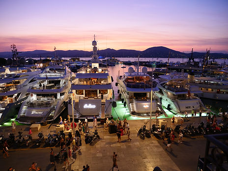 Chauffeur-driven limousines parked in front of a yacht at the port of Saint-Tropez