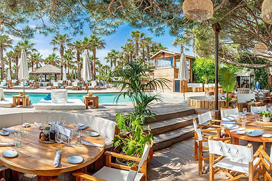 a well-set white table in front of tourists swimming in the pool of Nikki Beach in Saint-Tropez