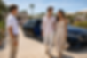 A Mexican tourist couple stepping out of a luxury limousine, greeted by a chauffeur in fro