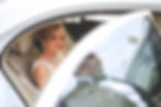 A bride seated in the back of a chauffeur-driven limousine