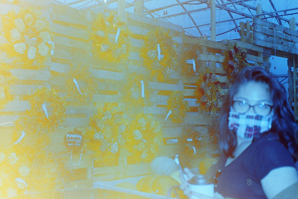 Woman with glasses and a mask starring at the camera. Half of the picture is tinted yellow due to light leaks