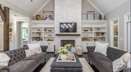 Cohesive living room design with neutral color palette, built-in shelves, stone fireplace, and balanced furniture layout.