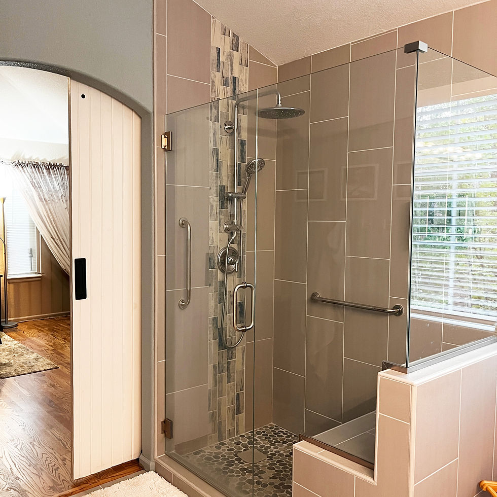 Glass-enclosed shower with beige tiles and pebble floor. Archway leads to a room with curtains and wooden floor. Bright and modern.