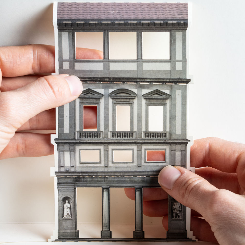 Nell'immagine mani che esplorano il pop up tattile del modulo architettonico degli Uffizi