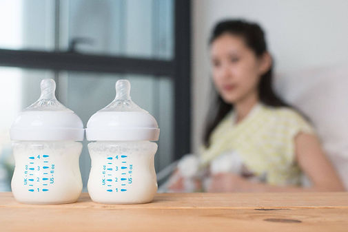 Mom pumping from both breasts with two full bottles in front of her