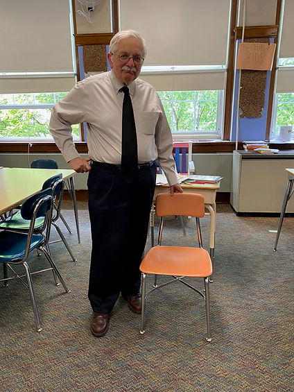 Dan Gill with an extra chair in his classroom