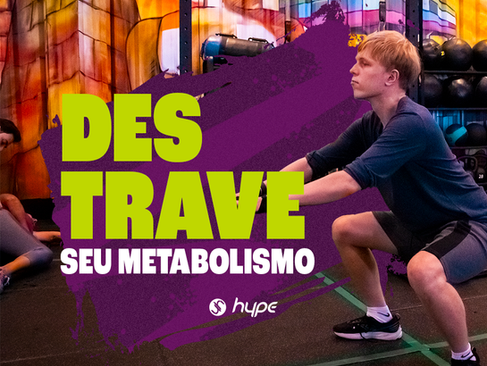 Homem faz agachamento na Academia Hype à frente, outros alunos estão alongando atrás