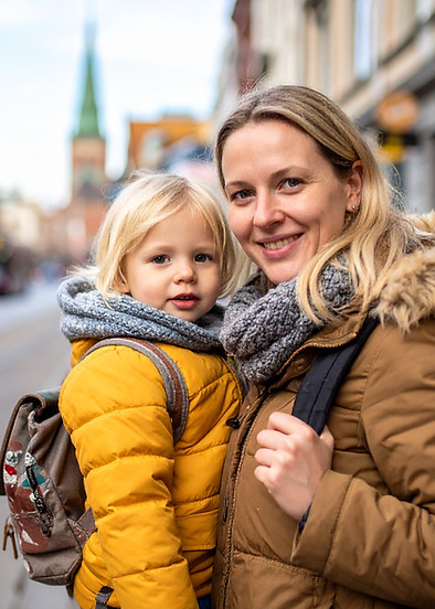 Mor som bærer en gutt i bymiljø.