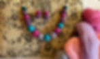 woollen bead necklace and earrings on a patterned fabric board and pieces of unspun wool
