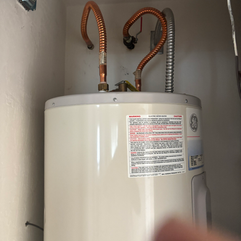 GE water heater with copper pipes installed in a closet