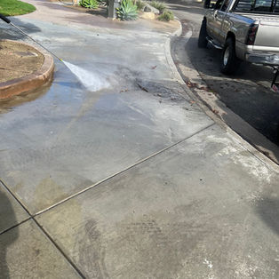 Close up action shot of high-pressure water blasting a concrete curb and driveway edge in Long Beach, CA