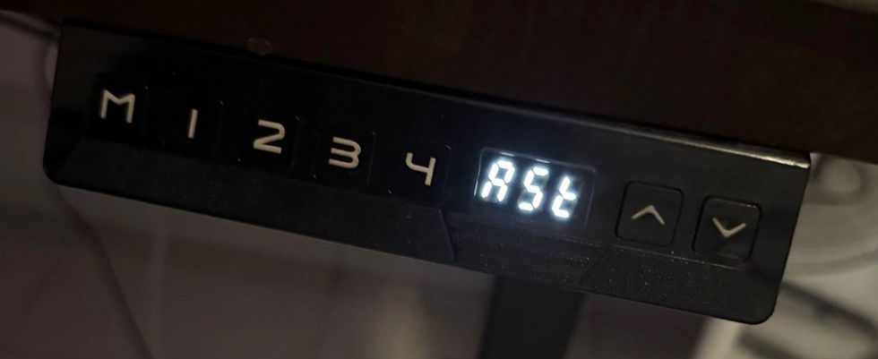 Close-up of a black adjustable desk control panel mounted under a wooden tabletop. The digital screen in the center illuminates the letters 'ASr', surrounded by memory preset buttons M, 1, 2, 3, and 4 on the left, and up and down arrow buttons on the right.