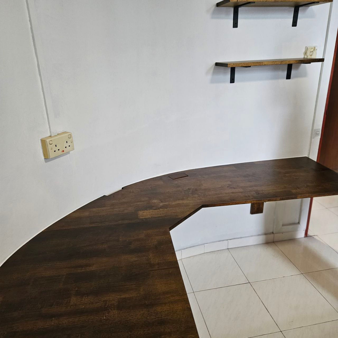 round Lshape desk mounted on a wall with two shelves in a corner, on a white wall